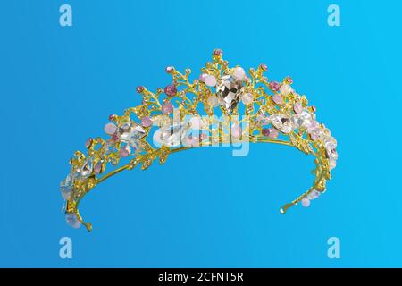 Gioielli oro corona tiara con diamanti e gemme isolato su sfondo blu Foto Stock