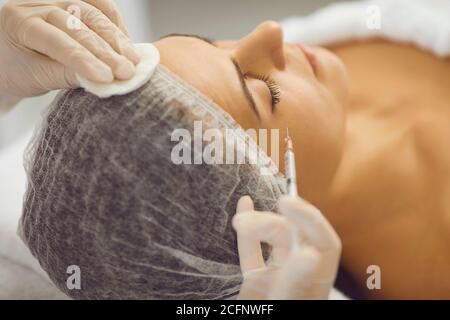 Mani di cosmetologa donna che fa iniezione di botox per la donna dentro salone di bellezza Foto Stock