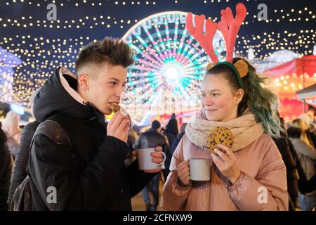 Ritratto di Natale invernale di felice adolescente ragazzo e ragazza a. mercato delle vacanze Foto Stock