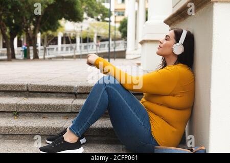 Donna caucasica curvilinea che ascolta la musica sul suo smartphone Foto Stock