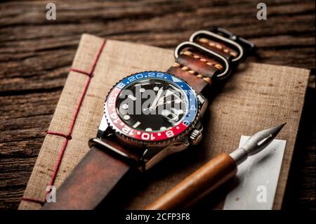 orologio da polso closeup di lusso da uomo con lunetta blu-rossa con quadrante nero e cinturino in pelle. Foto Stock