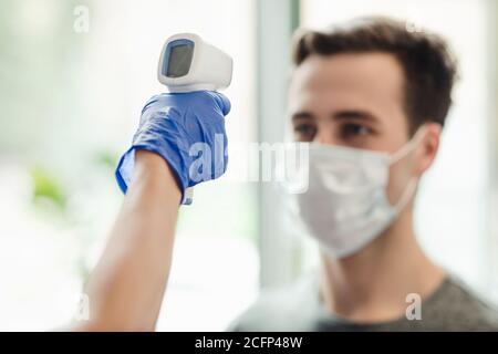 Manager controllo della temperatura corporea dell'uomo con termometro senza contatto Foto Stock