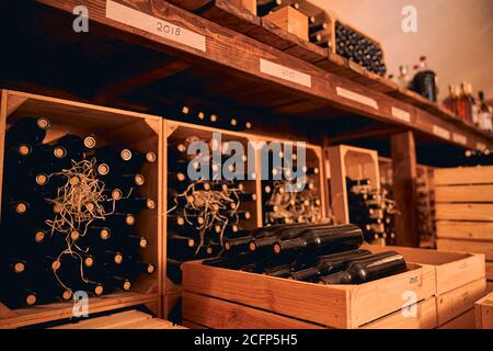 Bottiglie di vetro di vino immagazzinate in casse di legno e vino rack Foto Stock