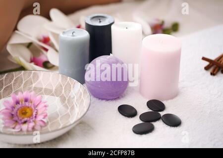 Basi per candele e spa su un asciugamano in bagno, asciugamano, pietra di mare, orchidee bianche. Set di prodotti Spa. Foto Stock