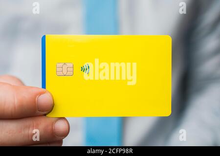 Uomo d'affari in camicia blu e cravatta tenere un vuoto carta di credito gialla tra le dita Foto Stock