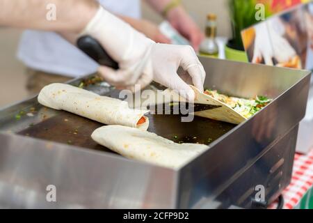 Mani in guanti, processo di preparazione di una fajitas o fajitos, cucina chef, autentico cibo di strada. Concetto di cibo nazionale Foto Stock