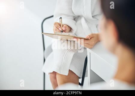 Donna adulta che scrive le sue raccomandazioni del medico Foto Stock