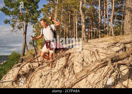 Jolly maschio andando nordic walking da solo nella foresta Foto Stock