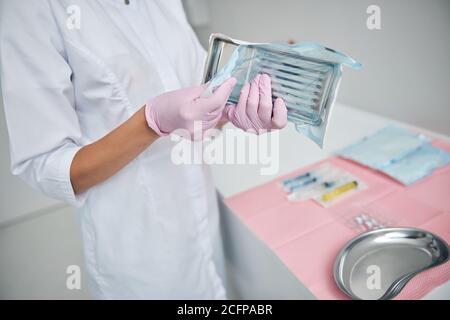 Medico in guanti in lattice che tengono uno strumento chirurgico Foto Stock