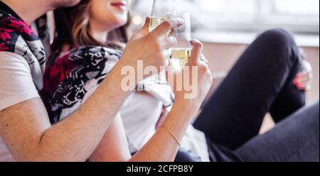 Uomo e donna in magliette bianche e maglie a maglia tenere bicchieri di champagne in mano Foto Stock