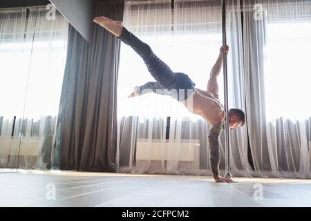 Attraente giovane uomo che balla in studio su pilone Foto Stock