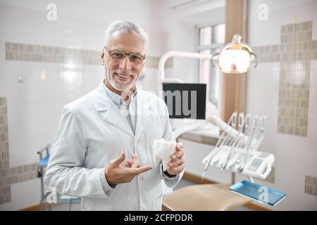 Dentista gioioso che tiene un modello grande del dente molare Foto Stock