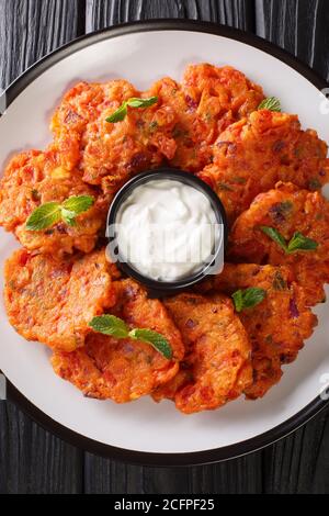 Domatokeftedes Ricetta frittelle di pomodoro greche servite con yogurt da vicino in un piatto sul tavolo. Vista dall'alto verticale Foto Stock