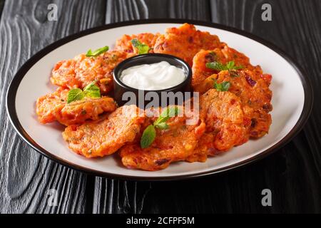 Deliziose frittelle di pomodoro greco con feta e menta servite con yogurt da vicino in un piatto sul tavolo. Orizzontale Foto Stock