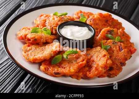 Frittelle di pomodoro greche servite con yogurt da vicino in un piatto sul tavolo. Orizzontale Foto Stock