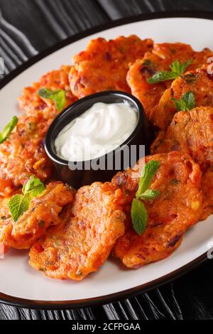 Domatokeftedes Ricetta frittelle di pomodoro greche servite con yogurt da vicino in un piatto sul tavolo. Verticale Foto Stock