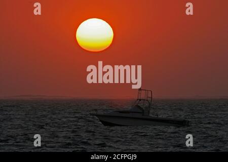 Tramonto sull'oceano Indiano a Ifaty in Madagascar. Una barca a motore che galleggia in mare aperto di fronte al tramonto, Madagascar Foto Stock