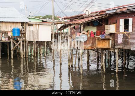 Kota Kinabalu / Malesia - 13 gennaio 2019: Famiglia musulmana seduto sul ponte di casa galleggiante sopra l'acqua a Kampung Tanjung Aru lama Foto Stock