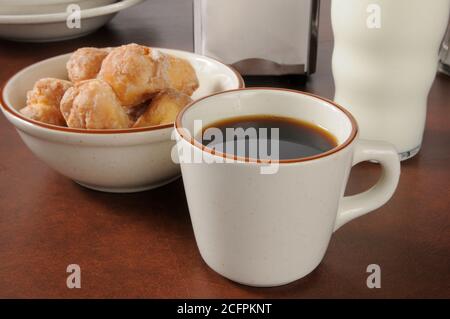 Una tazza di caffè con una ciotola di ciambelle Foto Stock