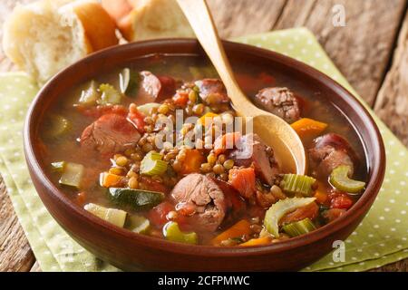 Zuppa di lenticchie con salsiccia piccante italiana primo piano in un piatto sul tavolo. Orizzontale Foto Stock