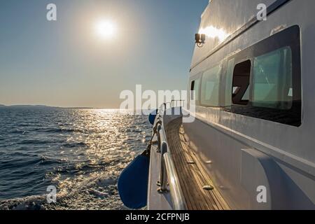 Giù dal lato dello yacht di lusso che viaggia attraverso l'oceano aperto con l'alba all'alba Foto Stock