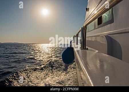 Giù dal lato dello yacht di lusso che viaggia attraverso l'oceano aperto con l'alba all'alba Foto Stock