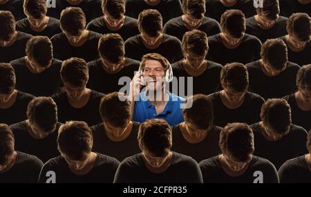 Vista dall'alto di una folla grigia di persone identiche e di un unico uomo speciale, concetto di differenza e diversità. Unico tra i senza volto, non come tutti gli altri. Parlare telefono, ascoltare musica, felice. Collage. Foto Stock