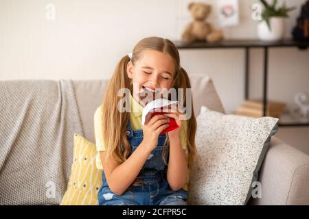 Ragazza che mangia cioccolato seduto su un divano a casa Foto Stock