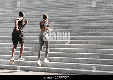 Coppia di joggers neri sportivi che corrono i passi in Parco urbano Foto Stock