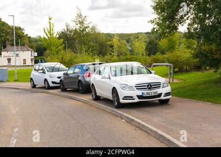 Tre auto parcheggiate su un marciapiede che blocca parzialmente il percorso per i pedoni. Foto Stock