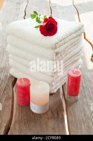 Pila di asciugamani bianchi spa e candele di rosa Foto Stock