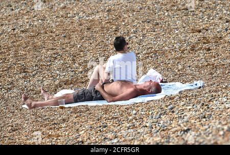 Brighton UK 7 settembre 2020 - prendere il sole sulla spiaggia come i visitatori godono il caldo sole d'autunno sul lungomare di Brighton oggi come tempo più caldo è previsto per più tardi questa settimana in tutta la Gran Bretagna: Credit Simon Dack / Alamy Live News Foto Stock