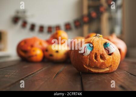 Primo piano di piccola zucca intagliata arancione con paillette occhi artificiali decorazione di Halloween, copia spazio Foto Stock