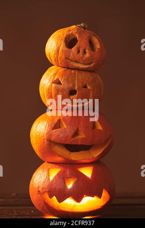 Gruppo di quattro pooky handmade Jack o' Lantern zucche composizione torre, studio girato, sfondo marrone Foto Stock