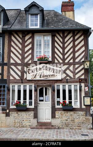 Facciata a graticcio del 'Café du Coiffeur' nel pittoresco francese Villaggio di Beuvron-en-Auge Foto Stock