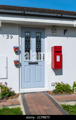 La porta anteriore di una casa residenziale con la propria parete personale montata scatola postale Royal Mail rossa, in Inghilterra, Regno Unito. Lo stile è vittoriano, ma forse replica. Foto Stock