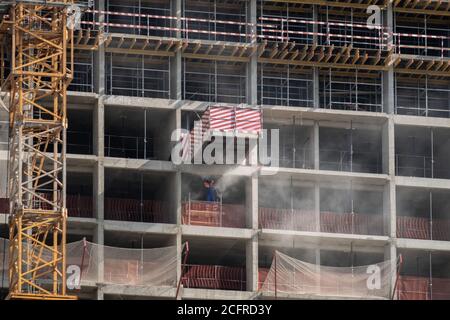 Vista della facciata di un edificio monolitico in cemento a più piani in costruzione. Recinzioni e strutture metalliche sui pavimenti. La polvere di cemento sta volando Foto Stock