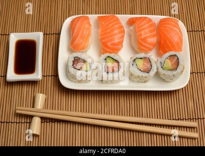 bastoncini di pollo, salsa di soia e sushi sul tappetino di bambù Foto Stock