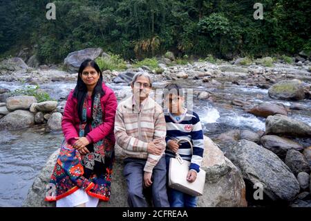 Primo piano di una famiglia indiana seduta sulle rocce di un fiume in Himalayan montagne di Gangtok, focalizzazione selettiva Foto Stock