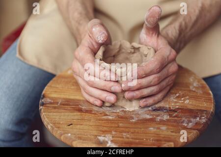 Il padrone crea un prodotto di argilla bianca. Le mani del padrone primo piano-in su sculpano un prodotto di creta usando una ruota del vasaio s. Il vasaio insegna la sua maestria apprendista. Foto Stock