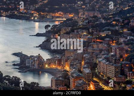 Veduta aerea della spiaggia e della città di Camogli sul Golfo Paradiso, Liguria, Italia al tramonto con edifici illuminati e riflessi sulla mangiatella Foto Stock