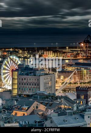 Vista aerea sul tetto del Porto Vecchio di Genova, Italia di notte con gli edifici lungomare, ruota panoramica e Bigo illuminati e una vista sugli opposi Foto Stock