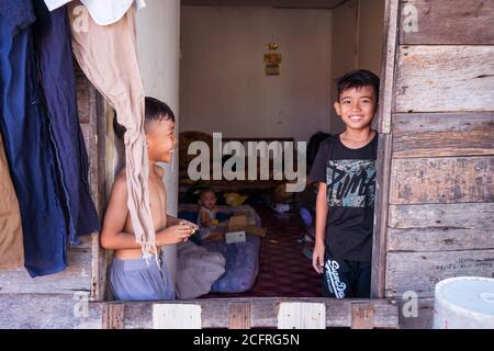 Kota Kinabalu / Malesia - 13 gennaio 2019: Tre fratelli che guardano la macchina fotografica alla porta di casa di legno in villaggio galleggiante Foto Stock