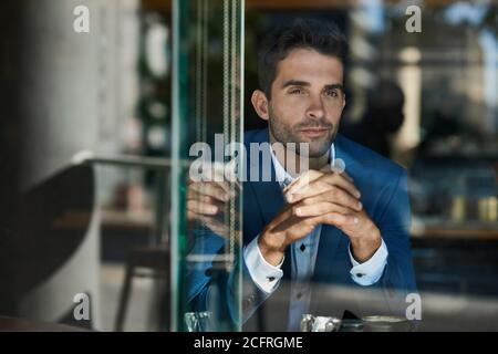 Giovane uomo d'affari che guarda attraverso la finestra di un caffè Foto Stock