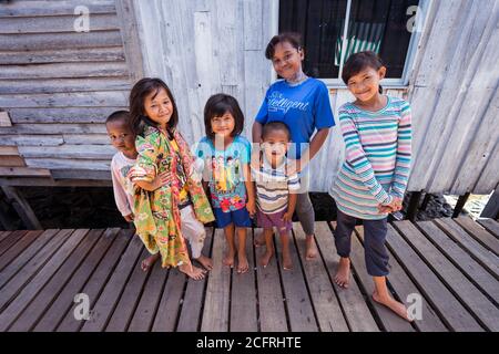 Kota Kinabalu / Malesia - 13 gennaio 2019: Gruppo di bambini felici che acclamano la telecamera che si pone nel villaggio galleggiante di Sabah chiamato Kampung Tanjung Foto Stock