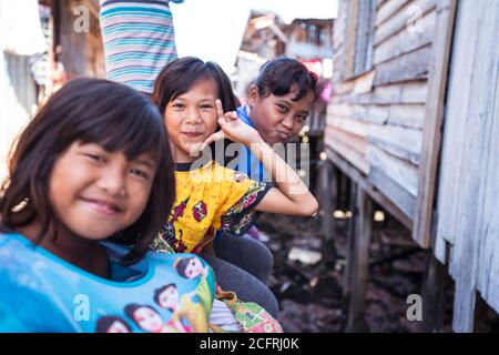 Kota Kinabalu / Malesia - 13 gennaio 2019: Gruppo di bambini felici che acclamano la telecamera che si pone nel villaggio galleggiante di Sabah chiamato Kampung Tanjung Foto Stock