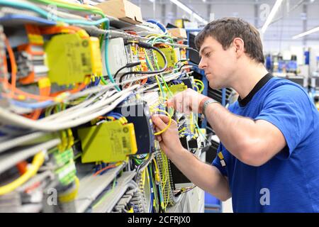 L'uomo assembla i componenti elettronici su una macchina in una fabbrica di ingegneria meccanica Foto Stock