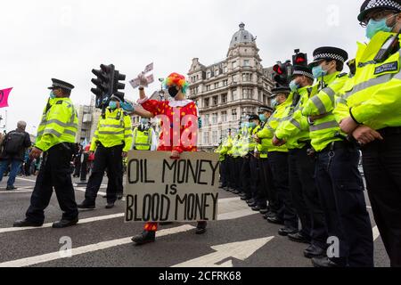 Il protetore in costume clown cammina oltre la polizia, 'Carnevale della corruzione' Extinction Rebellion dimostrazione, Londra, 3 settembre 2020 Foto Stock