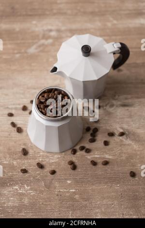 primo piano di caffettiera con chicchi di caffè su un tavolo di legno, studio Foto Stock