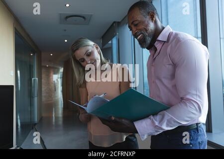 Uomo d'affari anziano che discute con giovane donna d'affari sopra i file Foto Stock